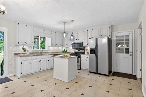 a kitchen with granite countertop a sink white cabinets and a window