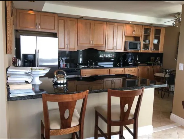 a kitchen with stainless steel appliances granite countertop a stove top oven a sink a dining table and chairs with wooden floor