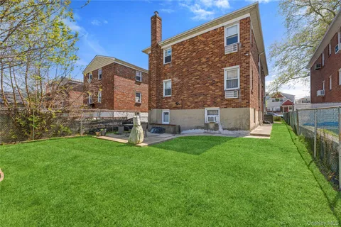 a view of a house with a yard and a large tree