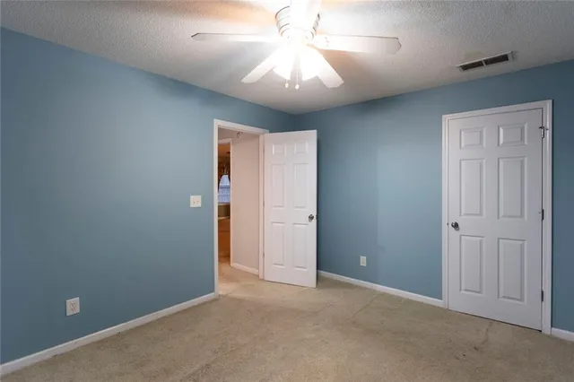 an empty room with closet and a chandelier fan