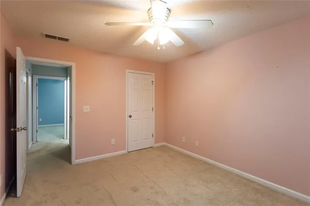 an empty room with a fan and a chandelier fan