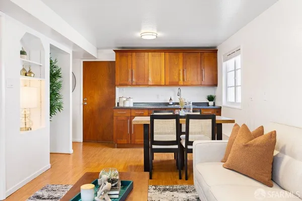 a living room with stainless steel appliances furniture a rug and a window