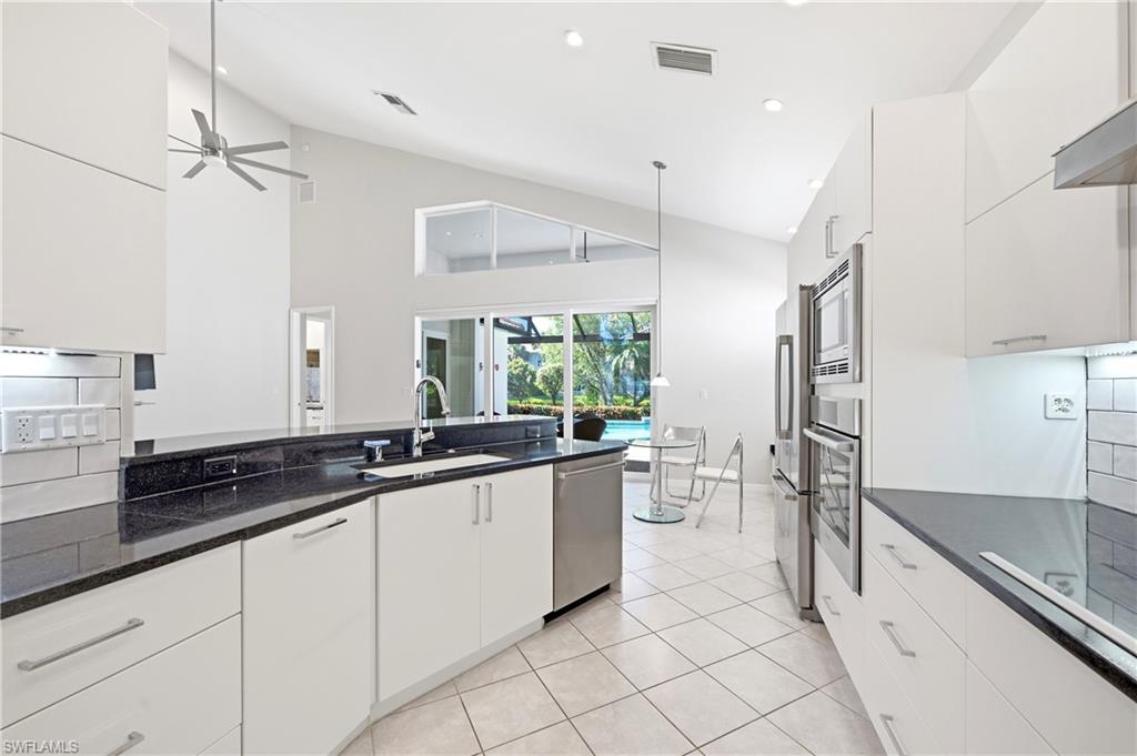 1960 Timarron Way Naples, FL 34109 - Photo 16 of 45 Contemporary kitchen featuring white cabinetry, black countertops, and stainless steel appliances