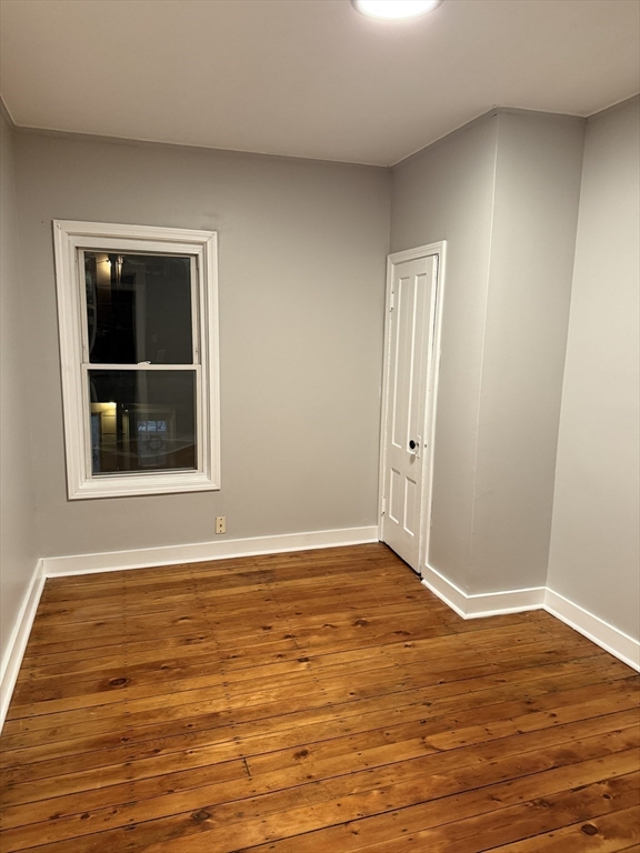 218 Vernon Street, Unit 3 Worcester, MA 01607 - Photo 7 of 8 a view of an empty room with wooden floor and a window