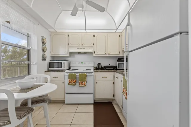 a kitchen with stainless steel appliances a white counter top space cabinets and a chair