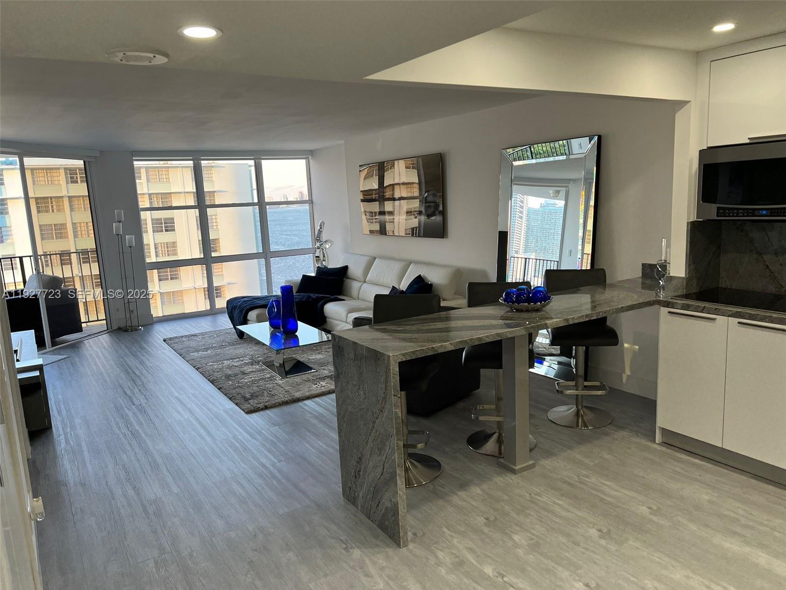 1865 Brickell Avenue, Unit A1607 Miami, FL 33129 - Photo 5 of 15 a living room with furniture a flat screen tv and a large window