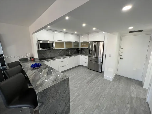 a kitchen with stainless steel appliances kitchen island granite countertop a refrigerator and a stove top oven