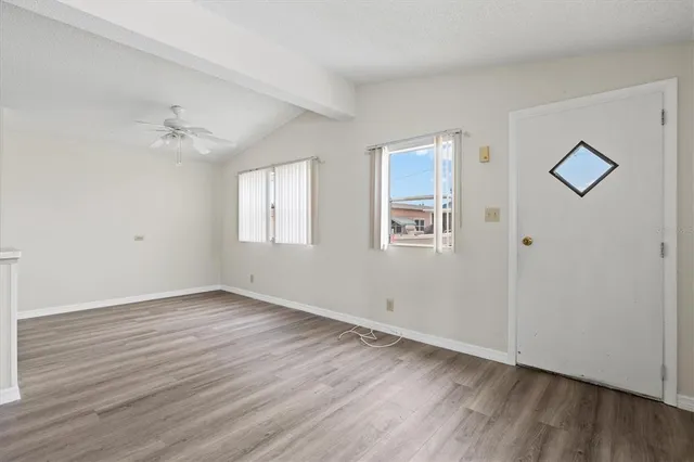 an empty room with wooden floor and windows