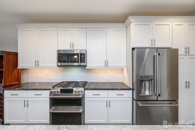 a kitchen with granite countertop white cabinets and stainless steel appliances