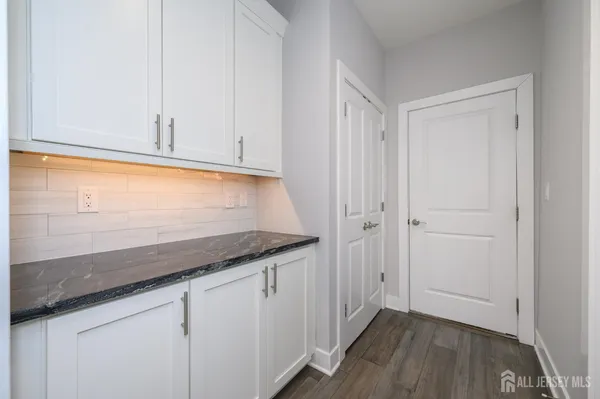 a kitchen with granite countertop white cabinets and a wooden floor