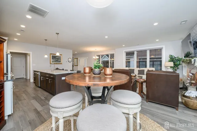 a kitchen with a dining table chairs sink and wooden floor