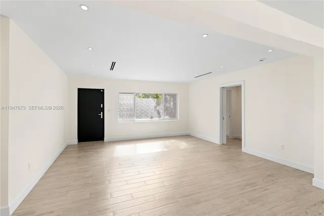 a view of an empty room with a window and wooden floor