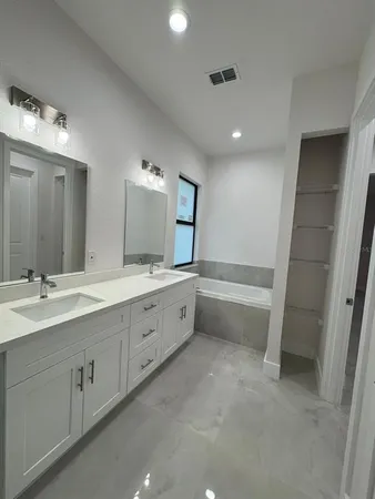 a bathroom with a double vanity sink a mirror and a bathtub