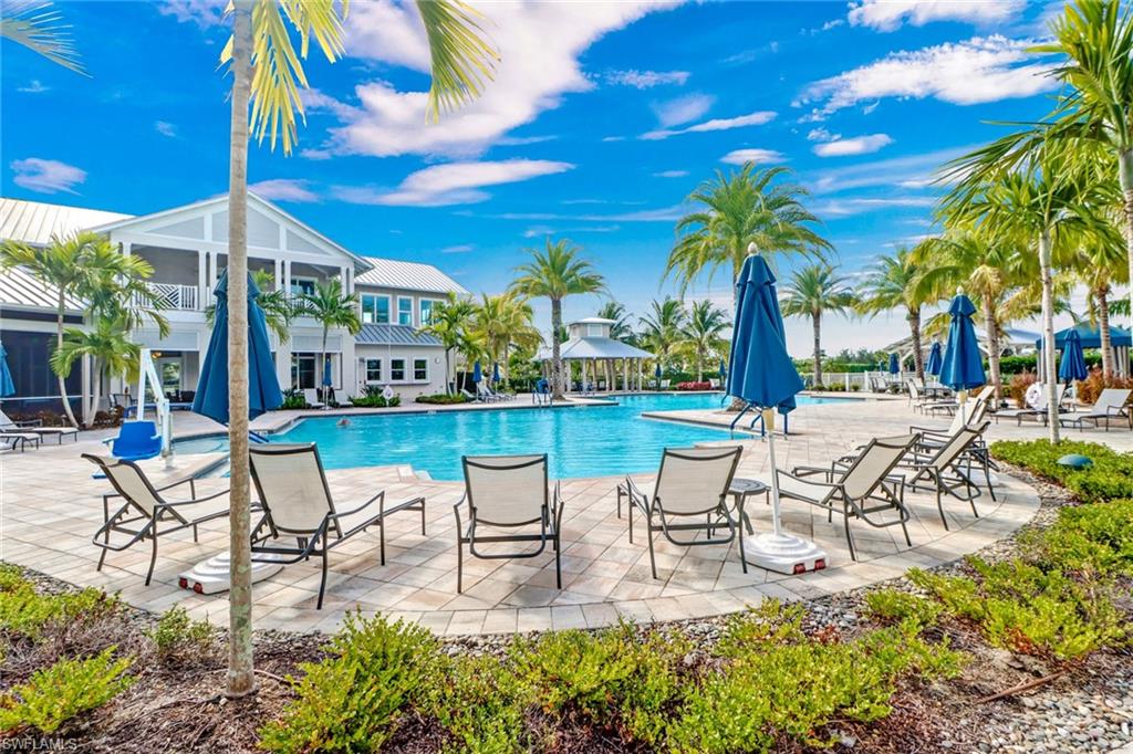 10588 Jackson Square Drive Estero, FL 33928 - Photo 36 of 50 a view of a patio with a table and chairs under an umbrella with palm trees