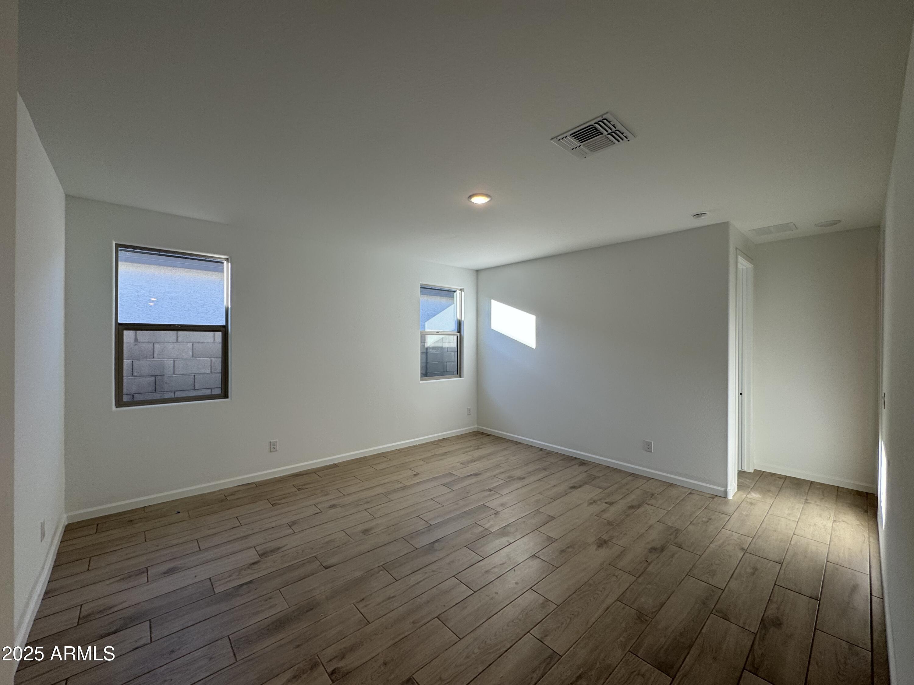 15720 West Camden Avenue Waddell, AZ 85355 - Photo 6 of 32 an empty room with wooden floor and windows