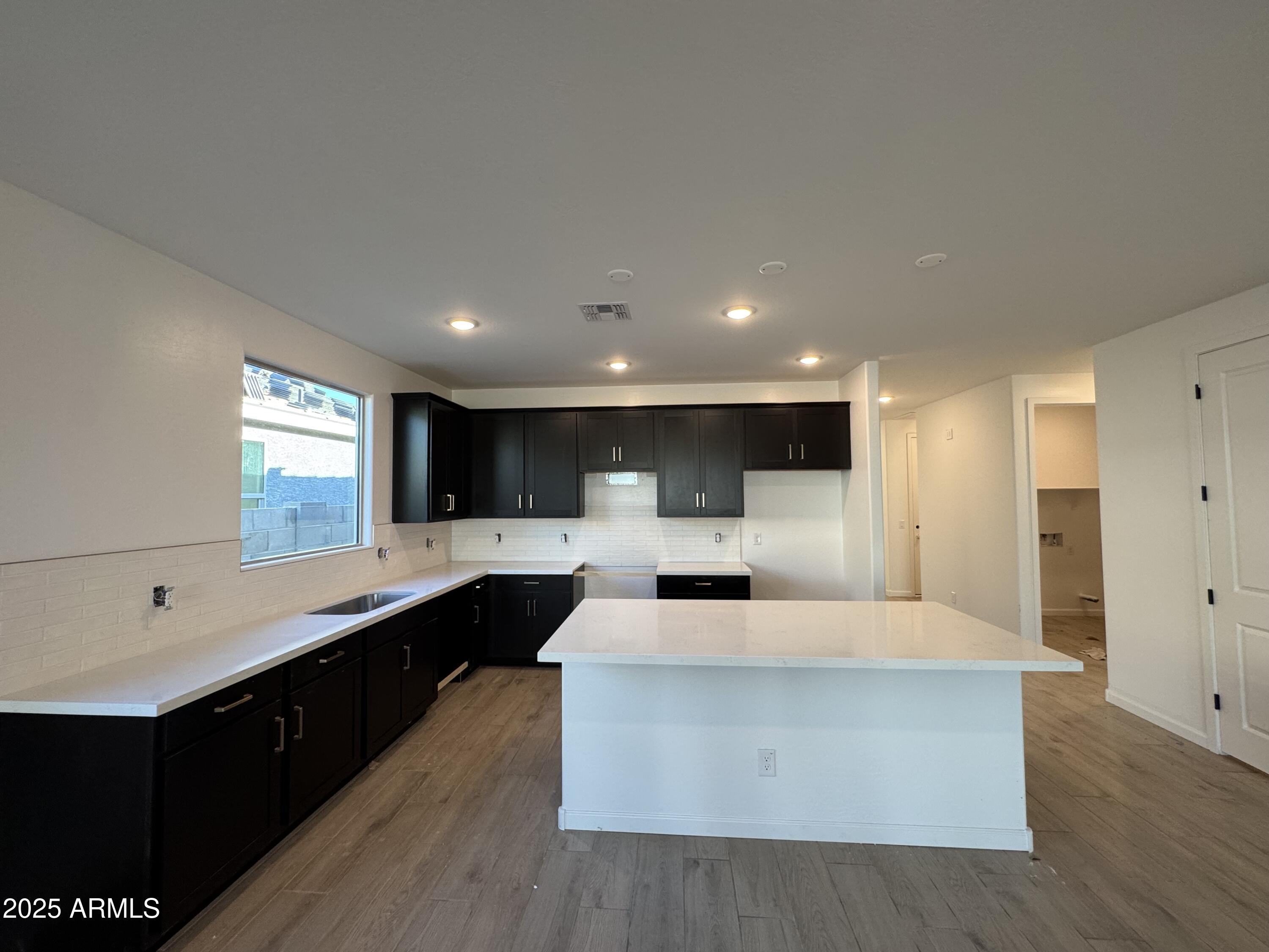 15720 West Camden Avenue Waddell, AZ 85355 - Photo 9 of 32 a large room with a large kitchen counter space and sink