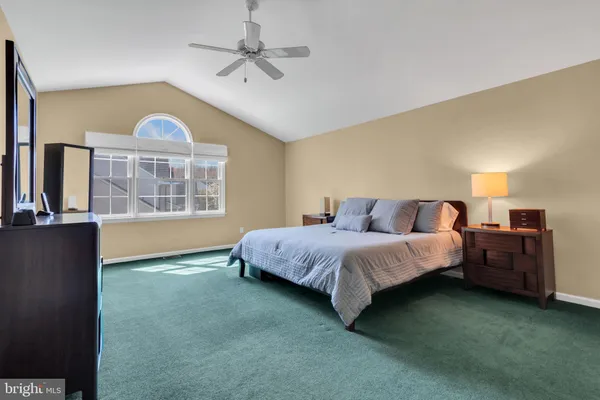 a spacious bedroom with a bed a dresser and windows