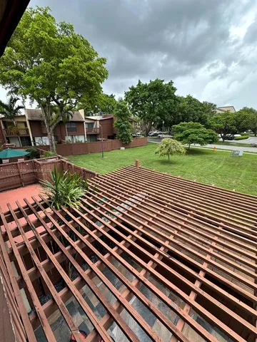 a view of a yard with plants and large trees