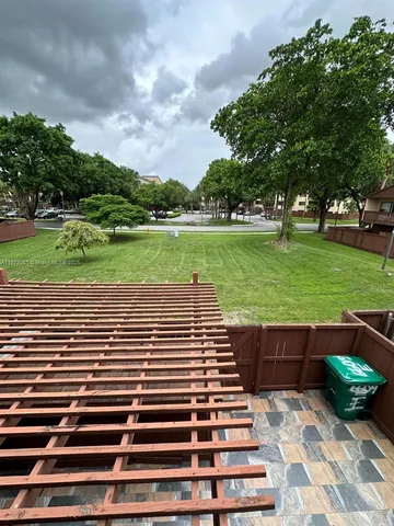 a view of a yard with plants and large tree