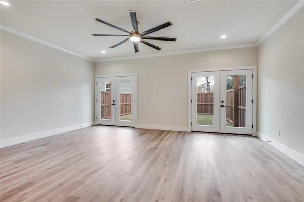 a view of an empty room with wooden floor and a ceiling fan