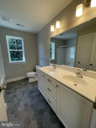 a spacious bathroom with a double vanity sink a mirror and a toilet
