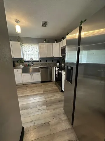 a large kitchen with stainless steel appliances granite countertop a stove a sink dishwasher and a microwave oven on the wooden floor