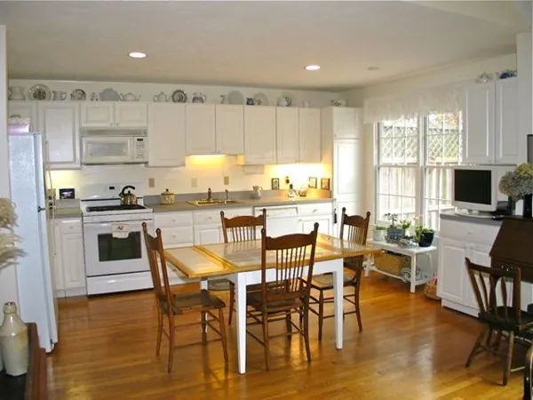 a kitchen with stainless steel appliances a table chairs refrigerator and cabinets
