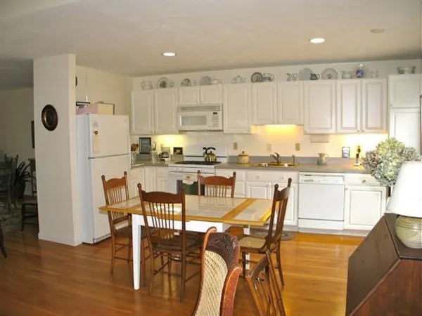 a kitchen with stainless steel appliances granite countertop a table chairs refrigerator and cabinets