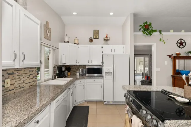 a kitchen with granite countertop a sink stove and cabinets