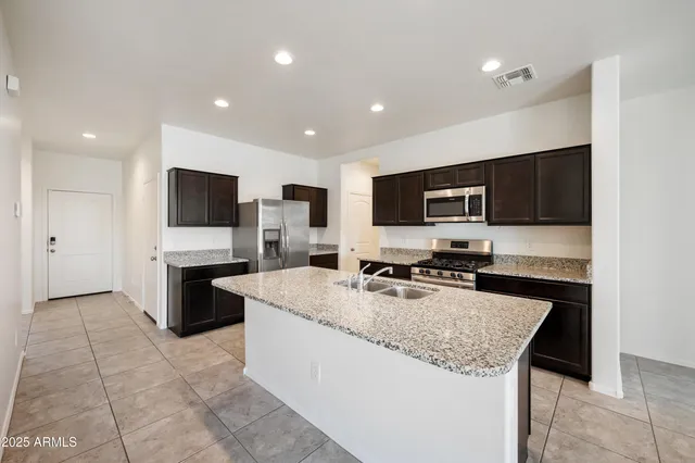a kitchen with granite countertop a sink a stove top oven a counter space and cabinets