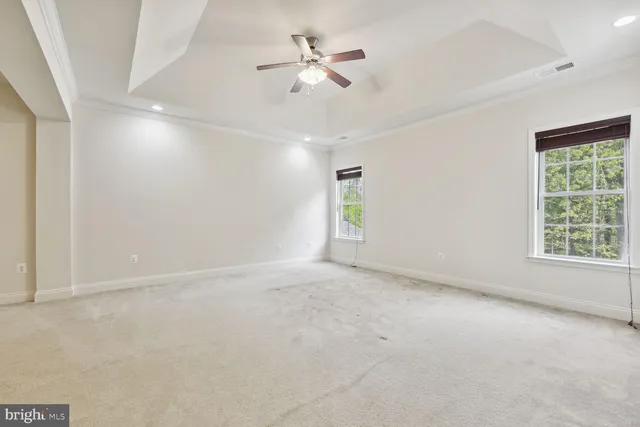 an empty room with windows and fan