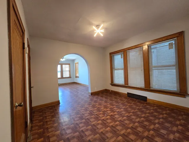 a view of an empty room with window and wooden floor