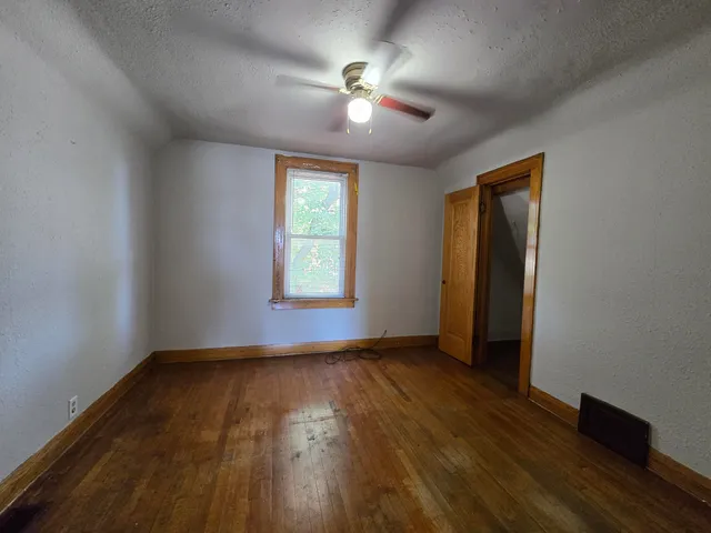 an empty room with wooden floor and a ceiling fan