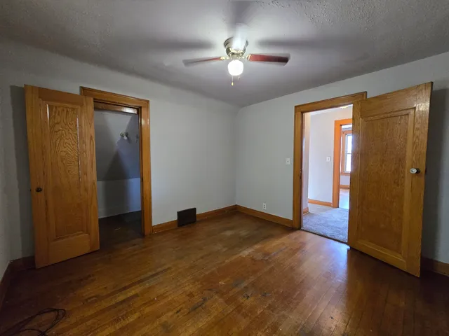 an empty room with wooden floor and a ceiling fan