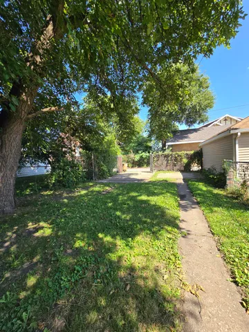 a backyard of a house with plants and large trees