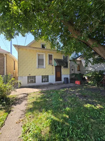 a view of a house with a small yard and large tree