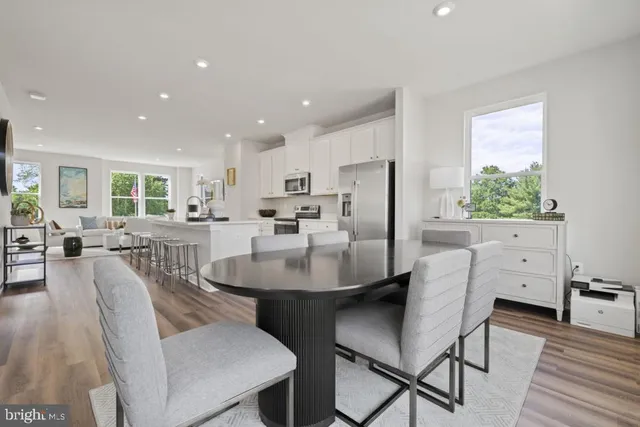 a dining room with furniture a large window and stainless steel appliances