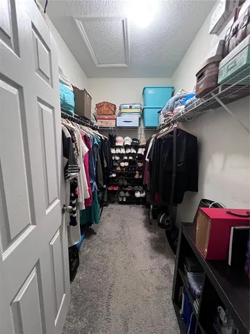 a view of walk in closet with clothes and shoes