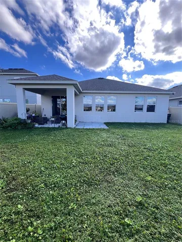 a view of a house with a yard and a large tree
