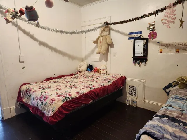 a bedroom with a bed and a dresser with wooden floor