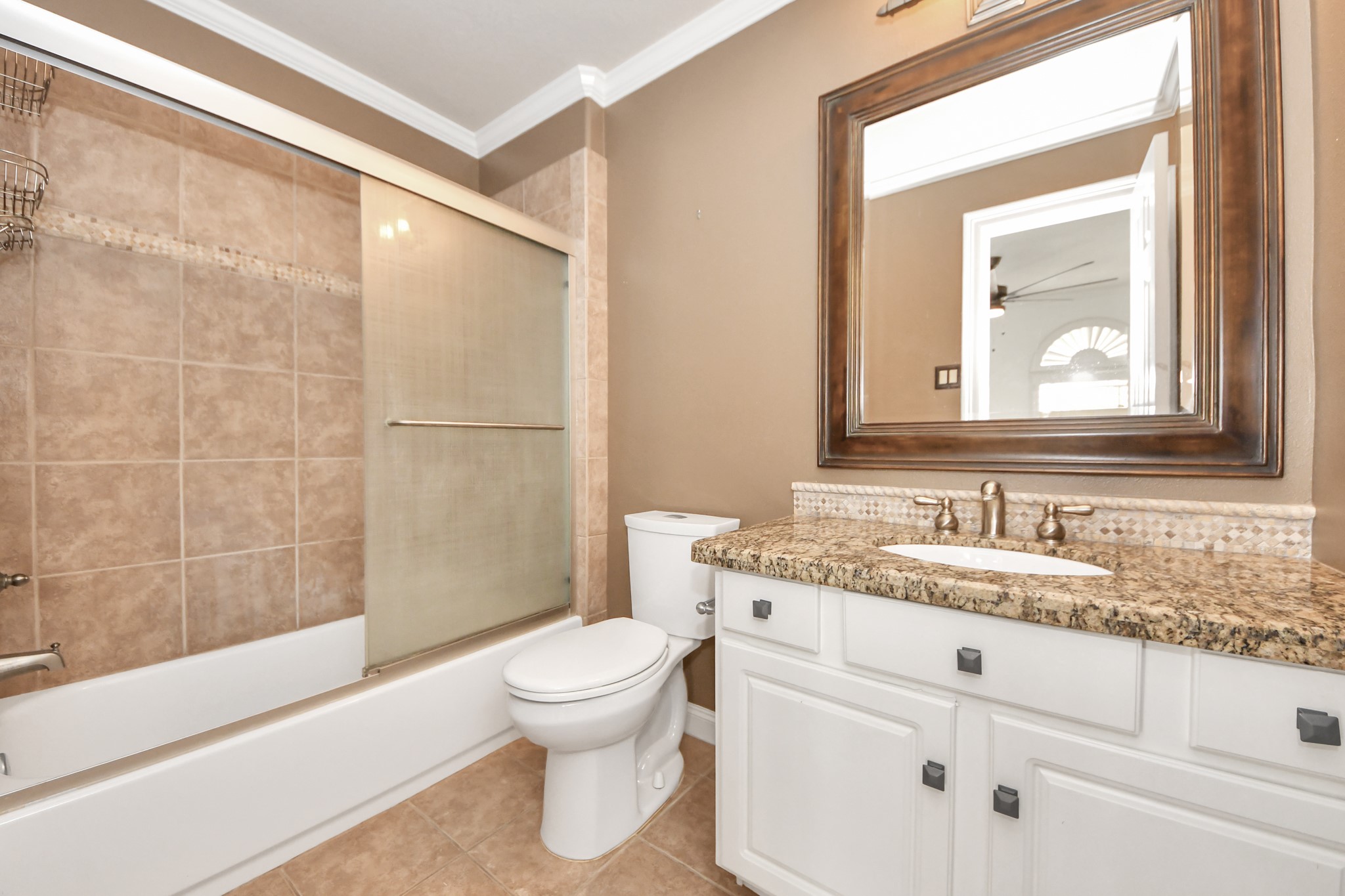 710 Jackson Hill Street Houston, TX 77007 - Photo 20 of 31 This attached bathroom features a modern design with a granite countertop, white cabinetry, and a large framed mirror. It includes a bathtub with a sliding glass door and tiled walls, offering a clean and elegant look.