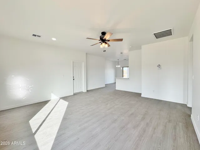 an empty room with chandelier fan and windows