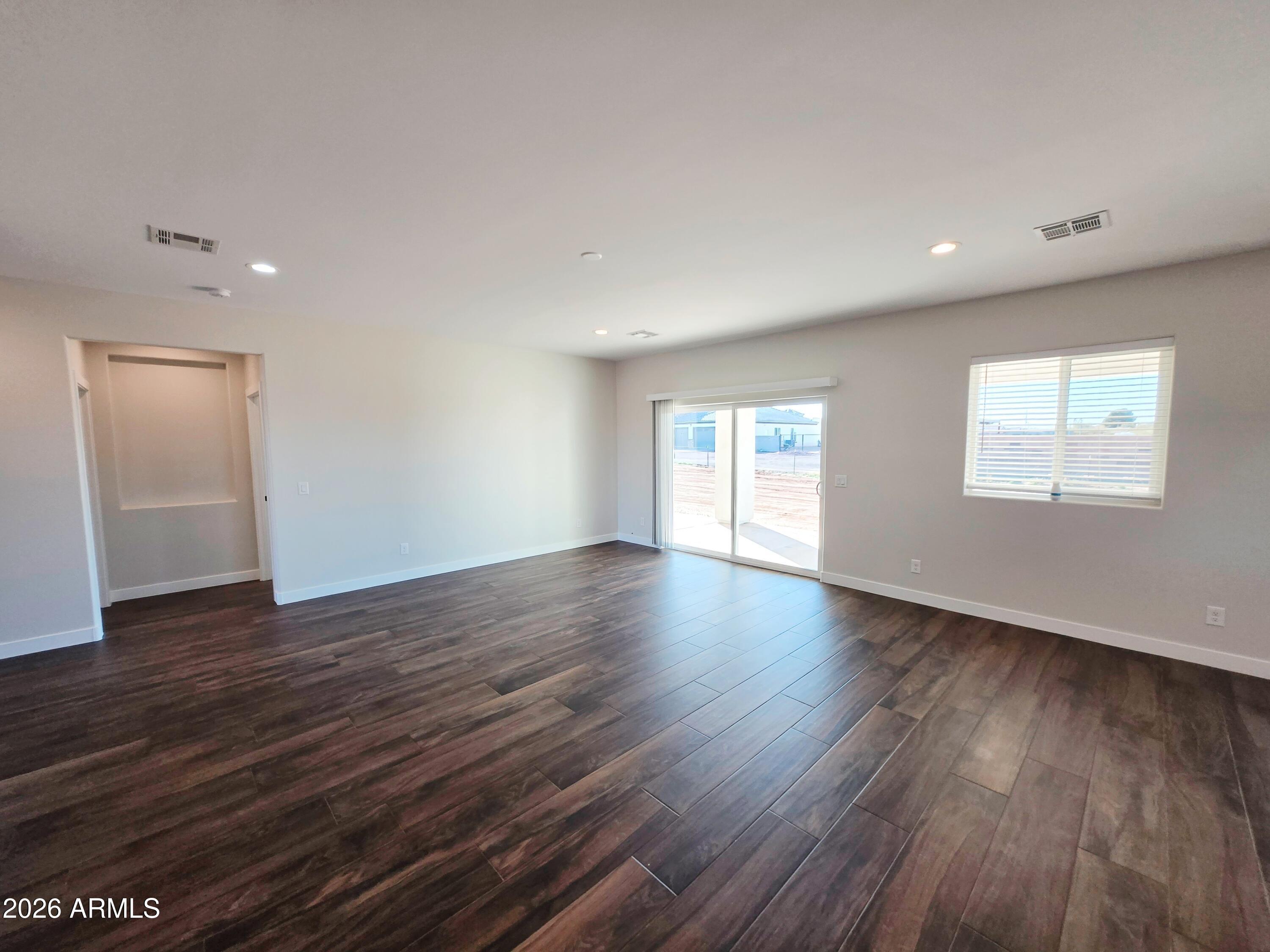 20735 West Elliot Road Buckeye, AZ 85326 - Photo 14 of 59 a view of an empty room with wooden floor and window