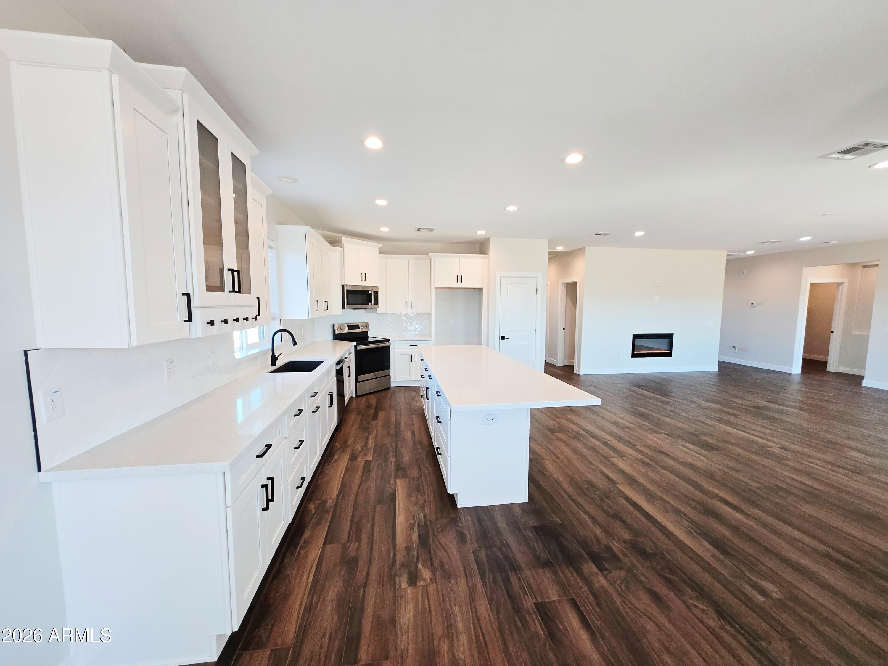 20735 West Elliot Road Buckeye, AZ 85326 - Photo 17 of 59 a large white kitchen with wooden floor and stainless steel appliances
