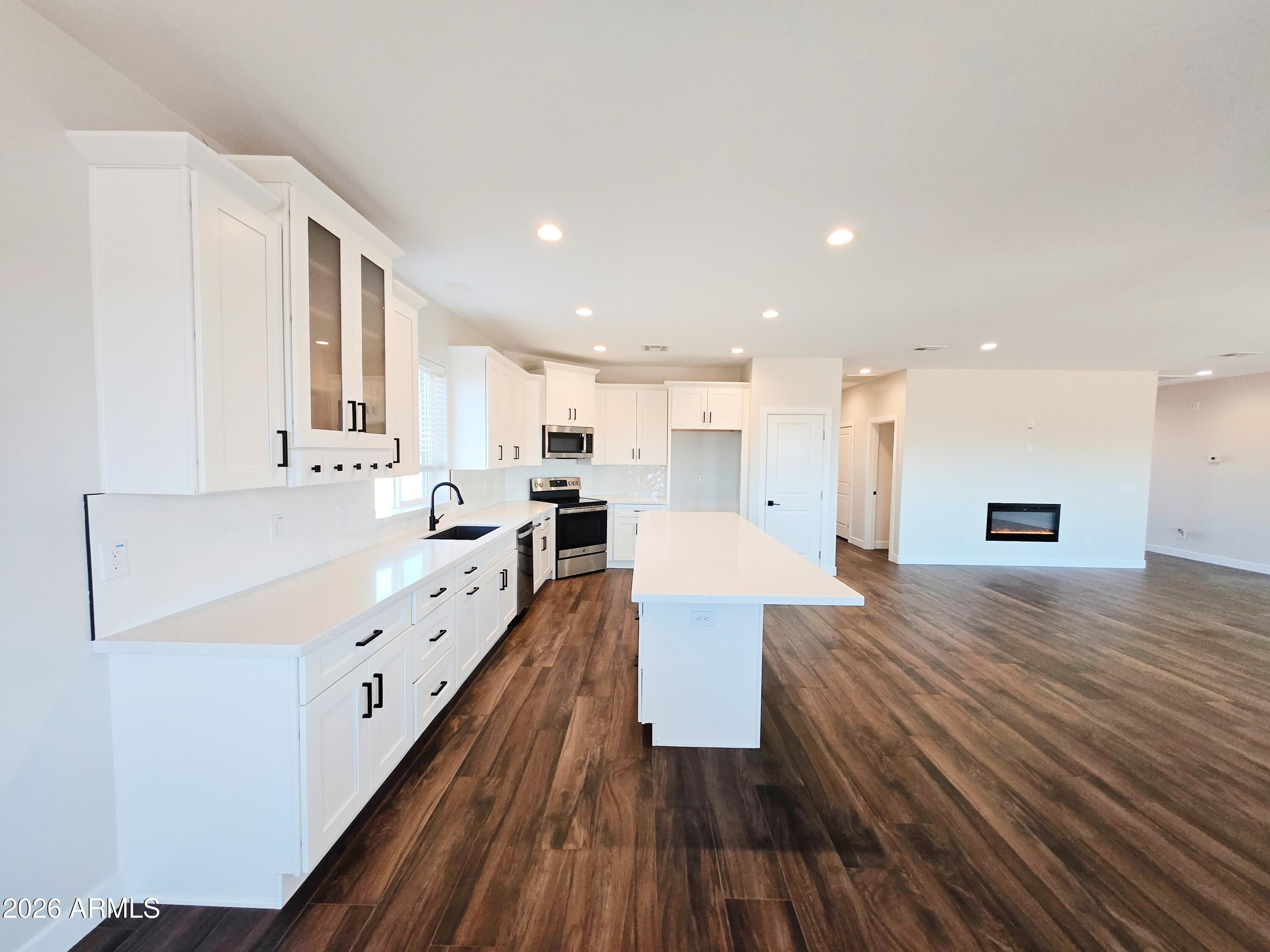 20735 West Elliot Road Buckeye, AZ 85326 - Photo 18 of 59 a large white kitchen with wooden floors and view living room