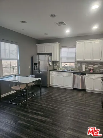 a kitchen with stainless steel appliances granite countertop a table chairs sink refrigerator and cabinets