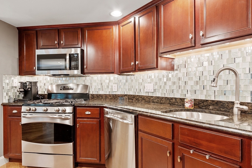 4 Sterling Hill Lane, Unit 424 Exeter, NH 03833 - Photo 6 of 24 a kitchen with granite countertop a sink stainless steel appliances and cabinets