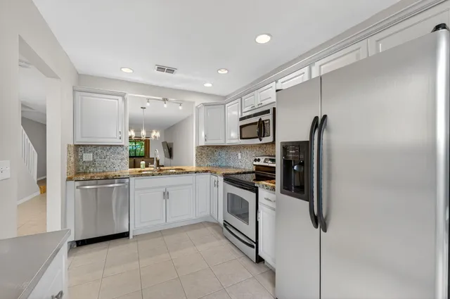 a kitchen with granite countertop a stove top oven cabinetry a refrigerator and stainless steel appliances