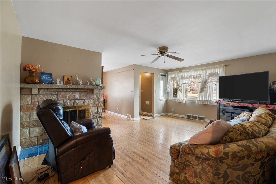 1527 Ridge Road Northwest Canton, OH 44703 - Photo 4 of 27 Living room featuring a stone fireplace, light hardwood / wood-style floors, and ceiling fan
