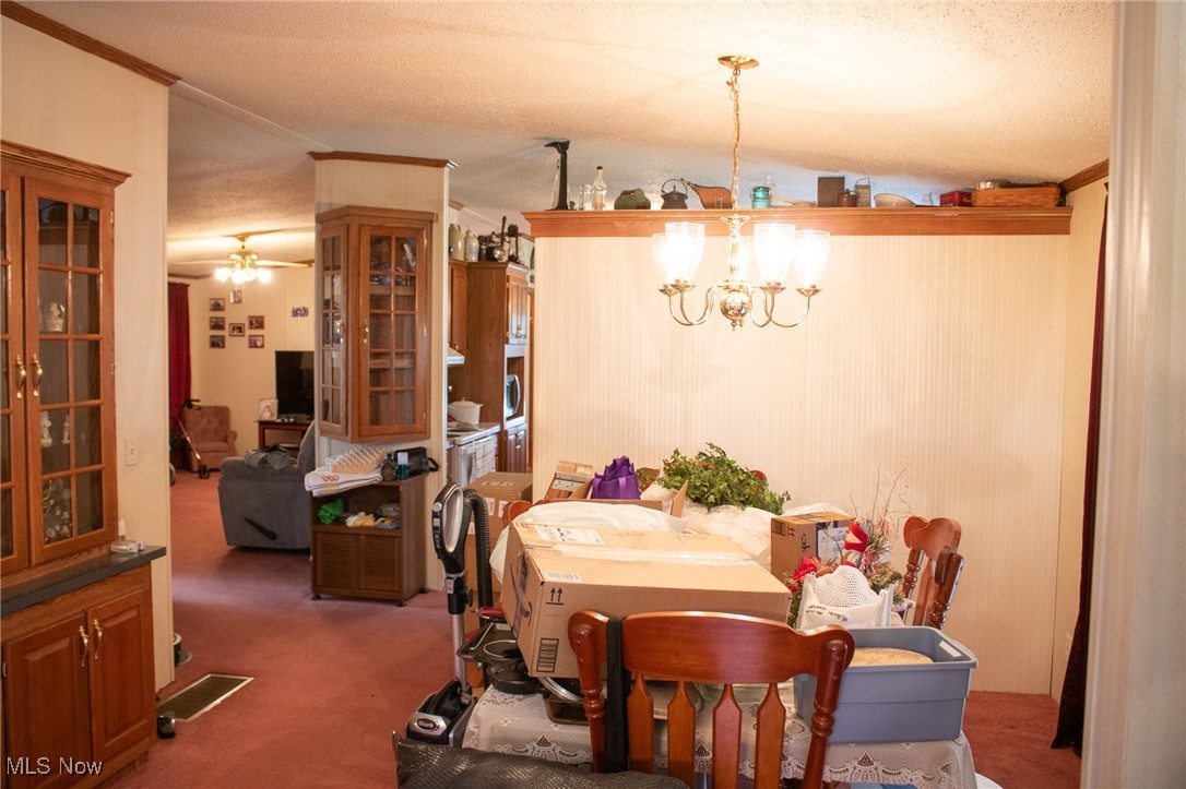 61691 Wintergreen Road Lore City, OH 43755 - Photo 11 of 50 Dining area featuring ornamental molding, carpet, ceiling fan, a textured ceiling, and a chandelier